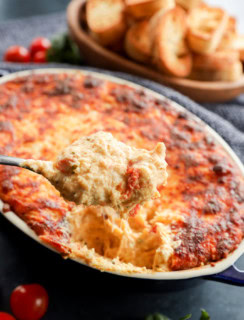 spoon lifting out four cheese baked appetizer from baking dish