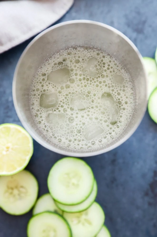 making a cucumber margarita in a cocktail shaker with fresh cucumber slices