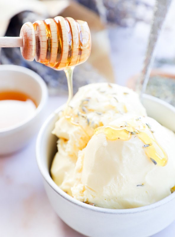 drizzling honey on frozen dessert in a bowl with a spoon and flowers