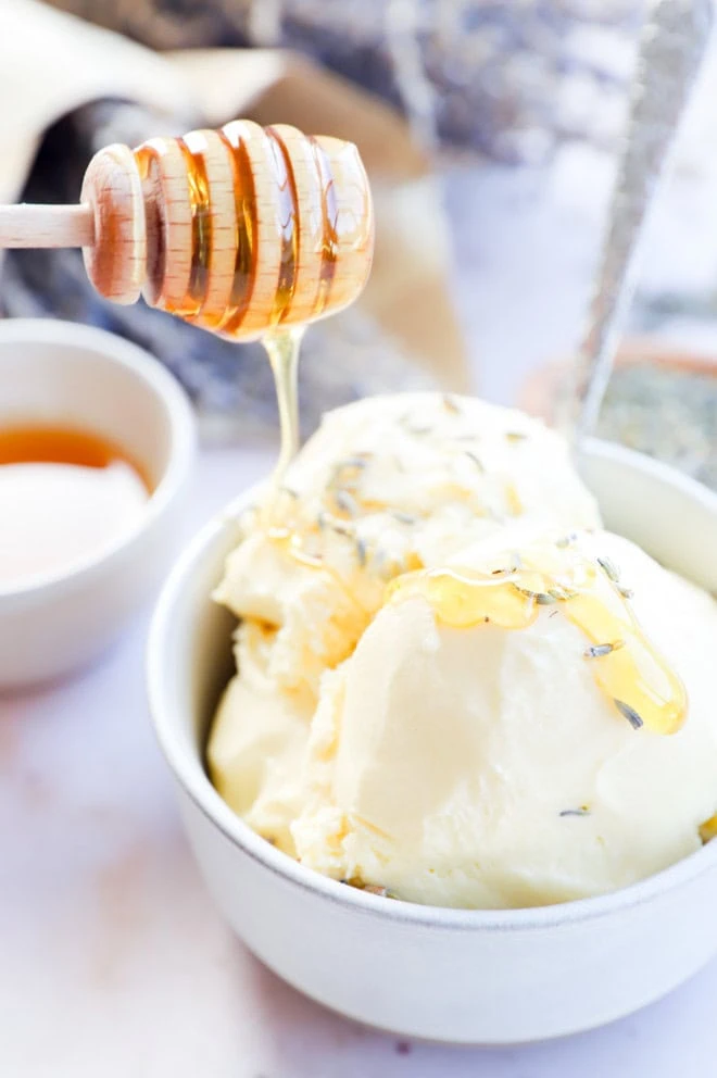 drizzling honey on frozen dessert in a bowl with a spoon and flowers