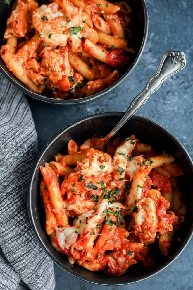 bowls of italian penne pasta with poultry tomato sauce and fresh herbs