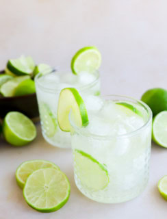 caipirinha cocktails in glasses with fresh limes all around