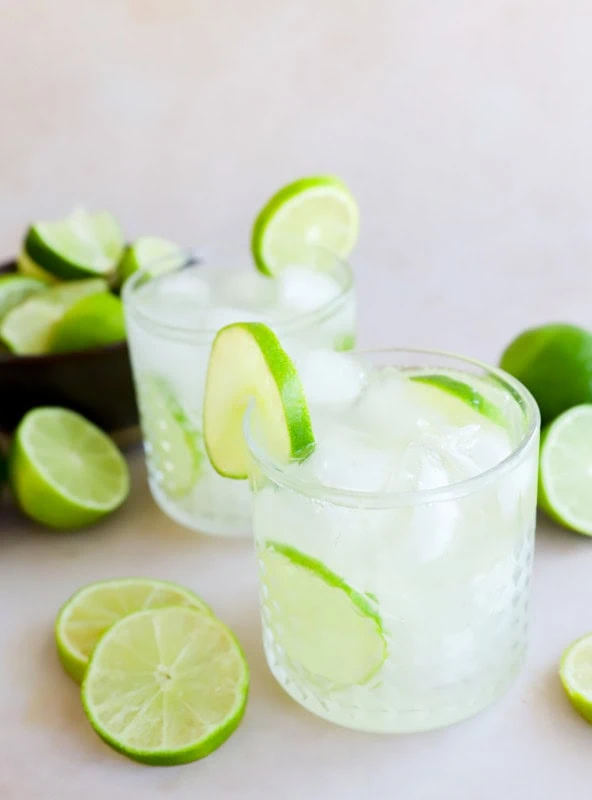 caipirinha cocktails in glasses with fresh limes all around