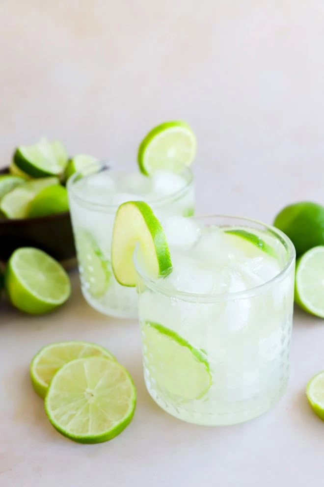 caipirinha cocktails in glasses with fresh limes all around