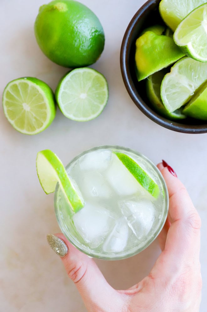 hand holding a glass filled with a caipirinha cocktail