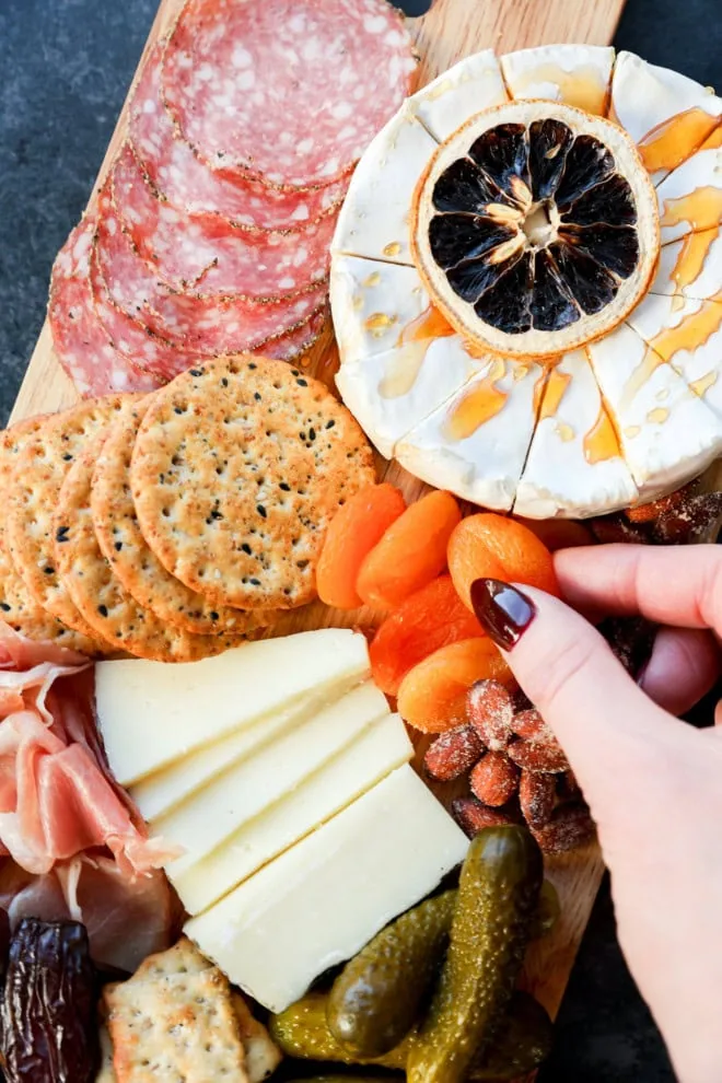 hand reaching into a snack spread to grab a dried apricot