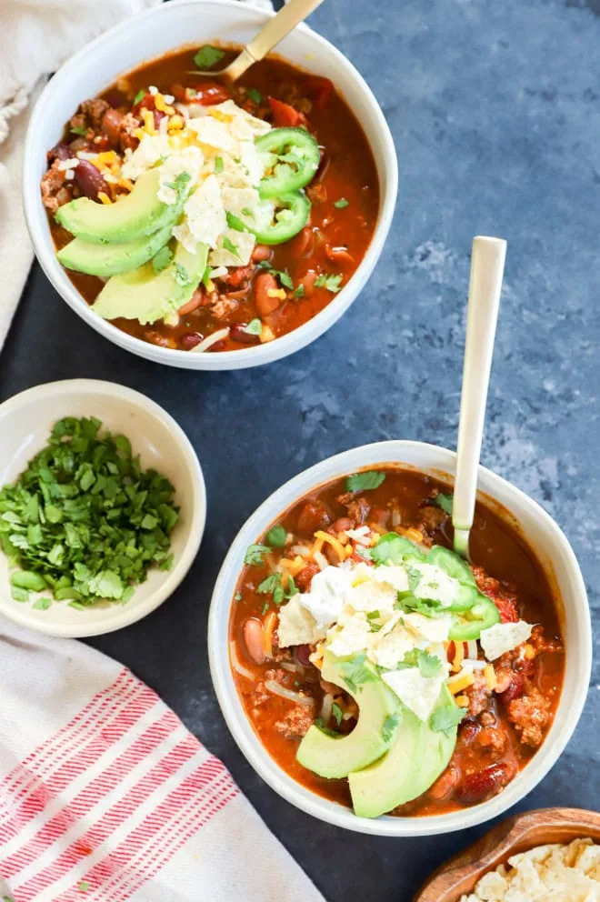 Bowls of soup with spoons and toppings on the side