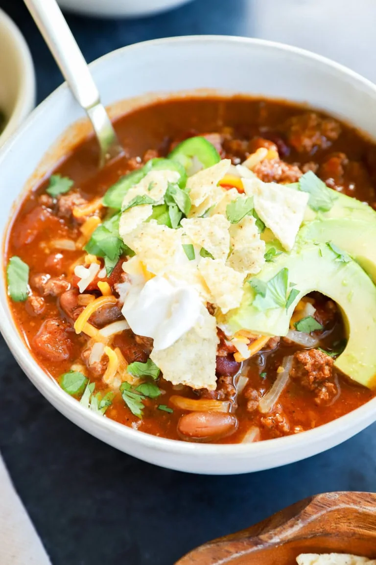 Spicy taco chili in a bowl with avocado, sour cream, and cheese