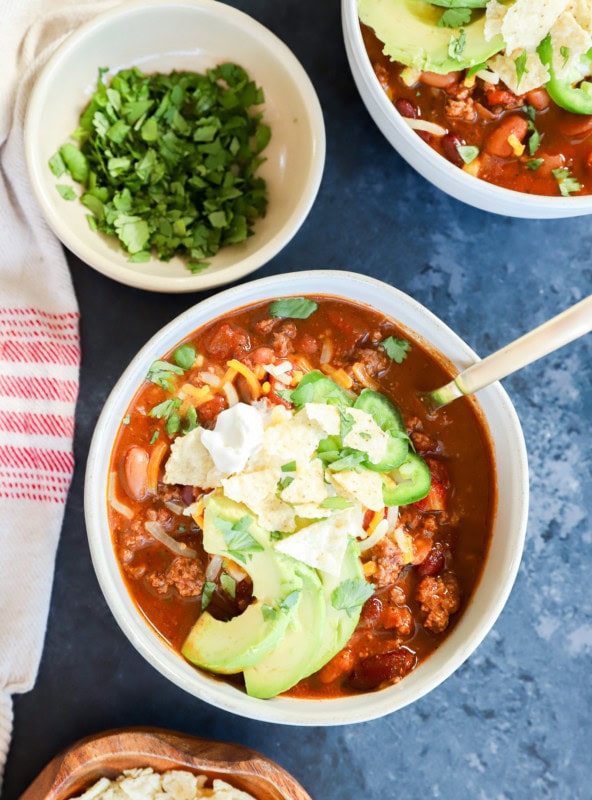 Bowls of taco soup with spoons and bowls with toppings