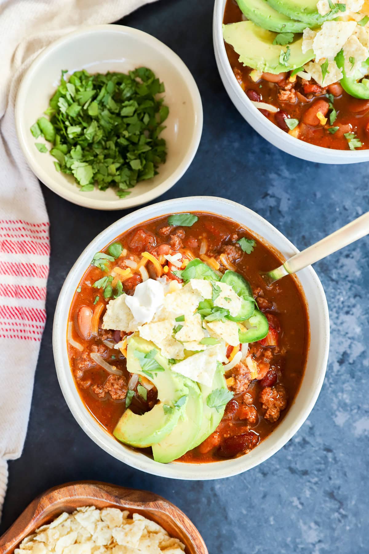 Bowls of taco soup with spoons and bowls with toppings