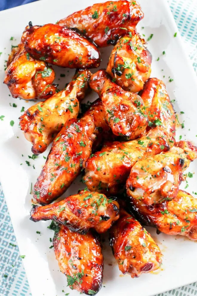 Grilled chicken wings with fresh herbs on platter with BBQ sauce