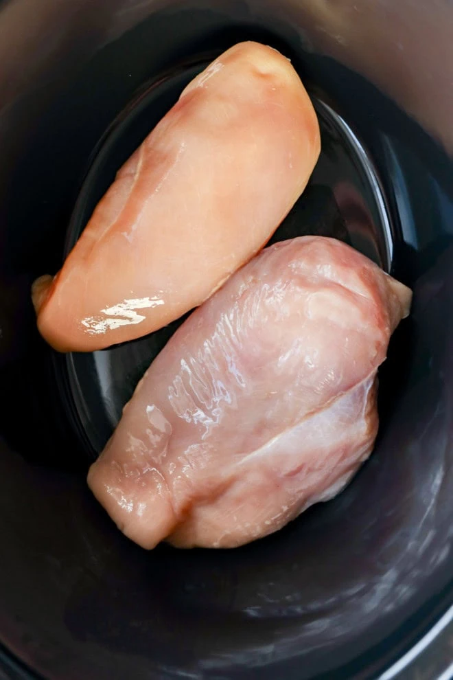 two chicken breasts in a slow cooker insert