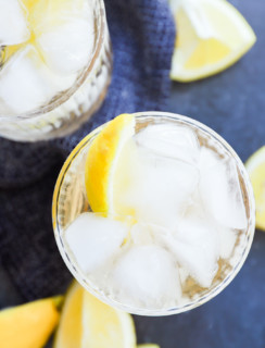 gin and ginger ale in glasses with lemon wedges and bar spoon