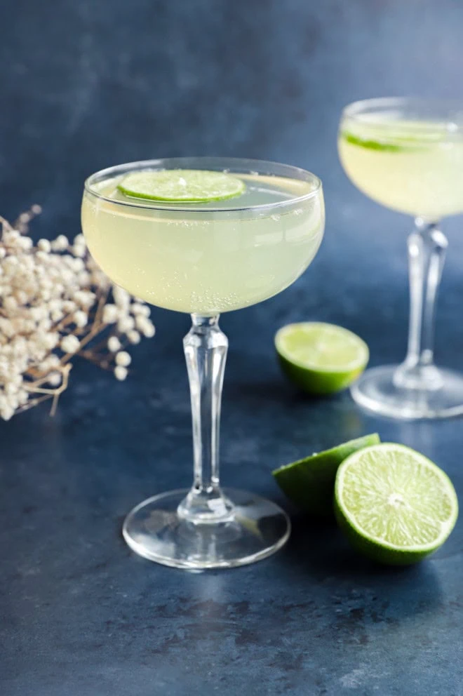 elderflower cocktail in coupe glass with lime wheel garnish