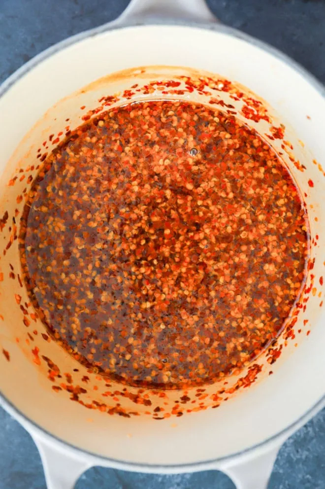 red pepper flakes and hot sauce in sweet liquid in a saucepan