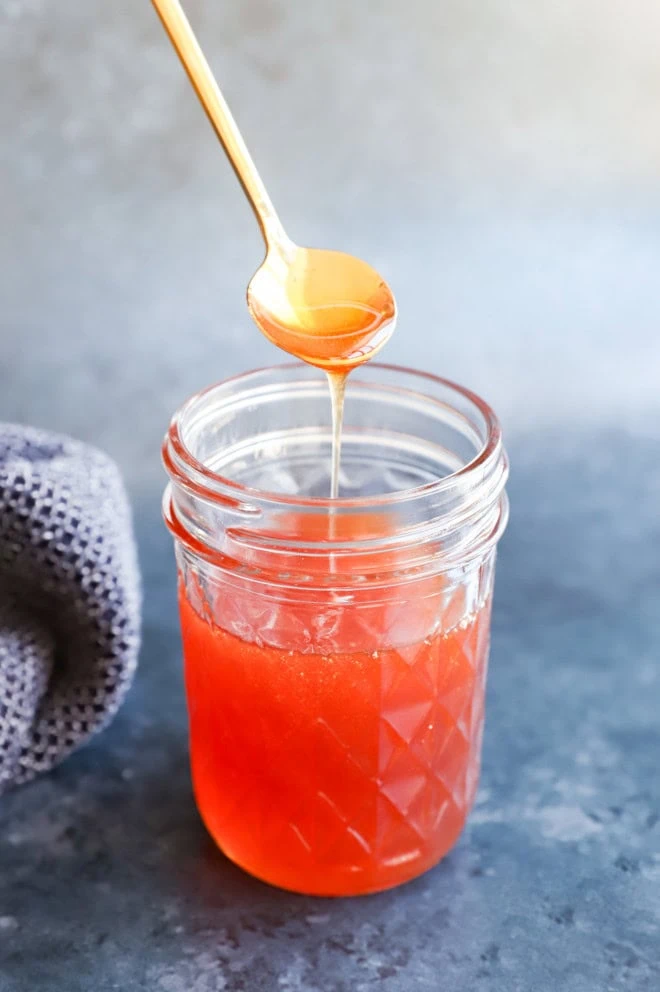 spooning hot honey with gold spoon from a jar
