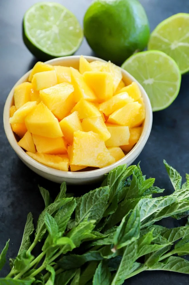 mango cut in a bowl with limes and fresh mint leaves