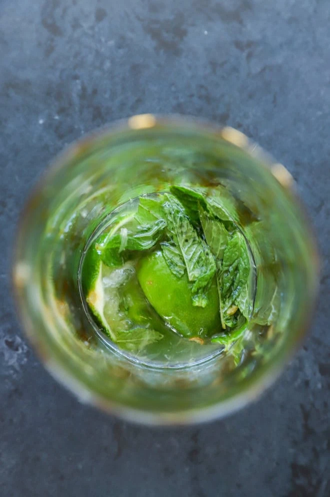 Muddled lime halves, mint leaves, and simple syrup