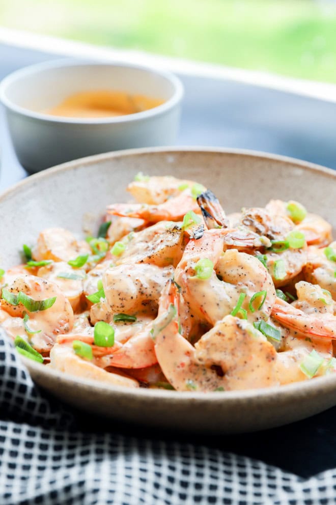 bang bang shrimp in a bowl with sauce and scallions