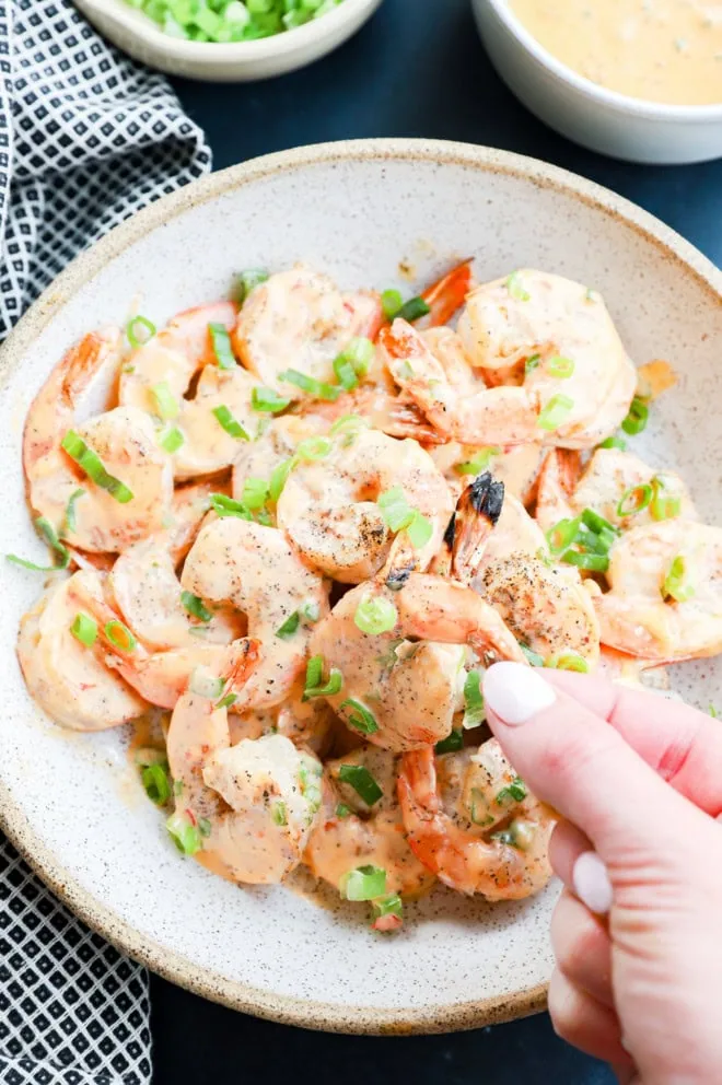hand holding shrimp over a bowl of shrimp