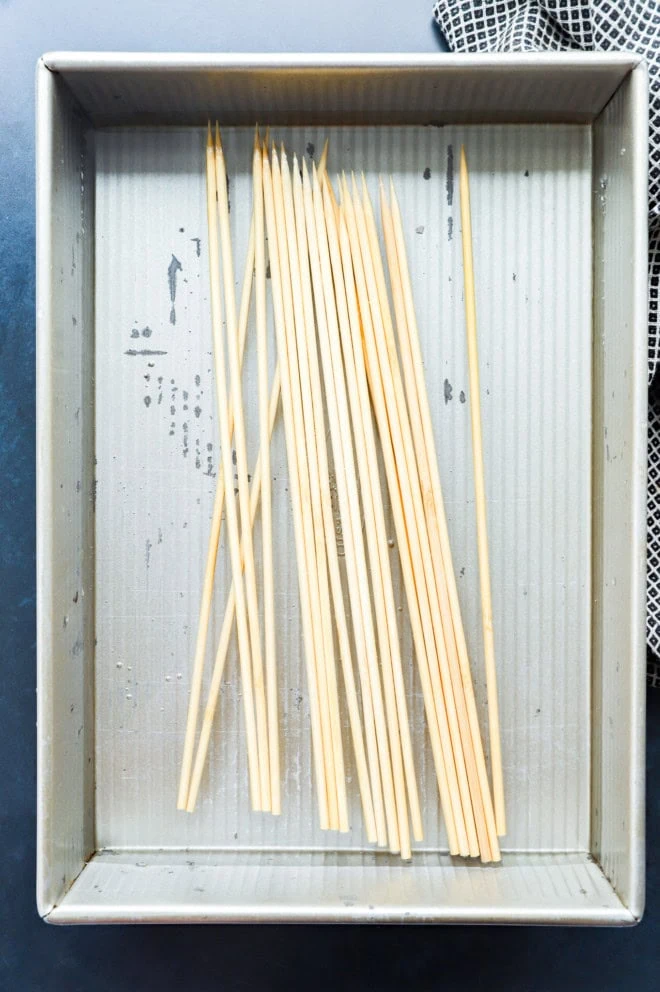 wooden skewers soaking in water in a shallow container