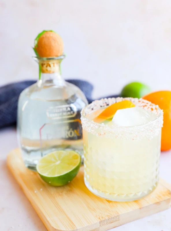 Patron bottle with a margarita in a salt rimmed glass and citrus garnish