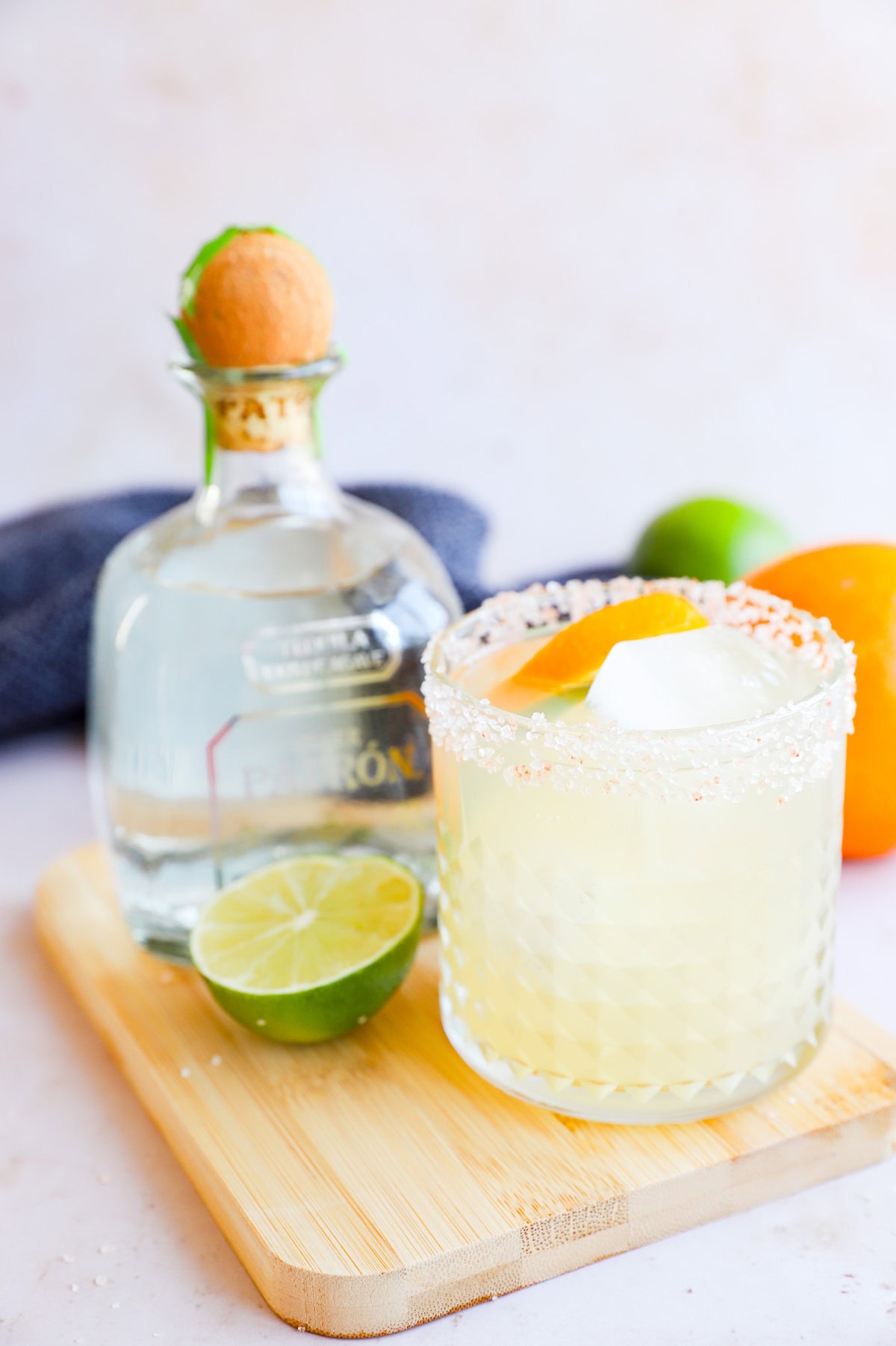 Patron bottle with a margarita in a salt rimmed glass and citrus garnish
