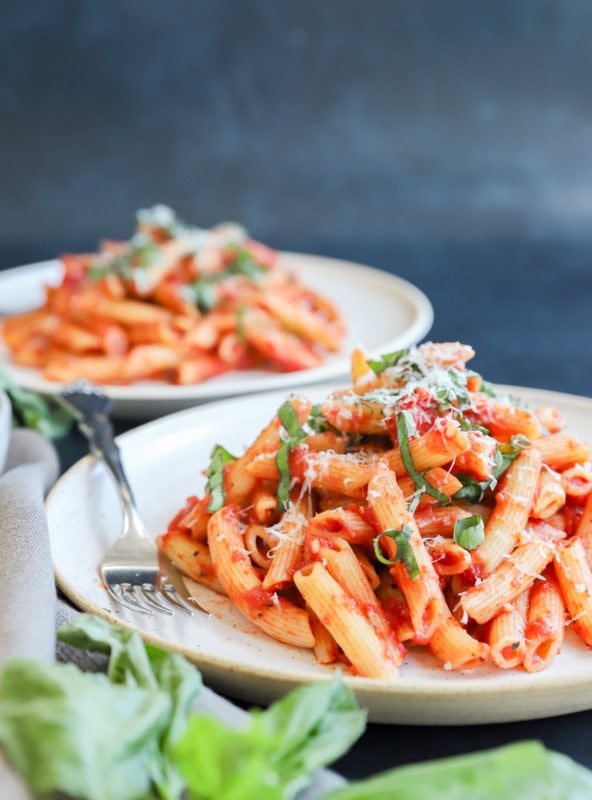 Penne pomodoro on plate with fresh basil on top and cheese