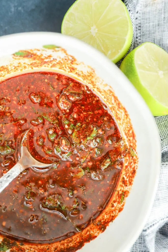 mexican chicken marinade in a bowl with spoon and fresh lime halves