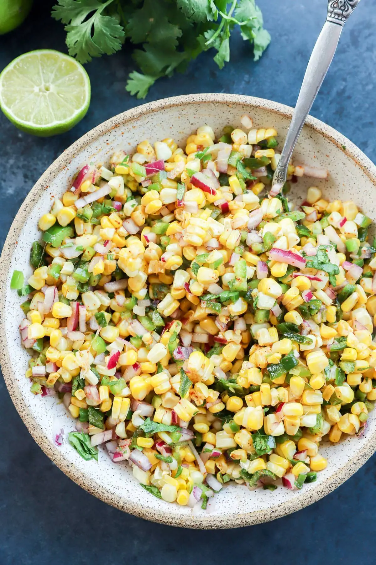 roasted chili corn salsa in a bowl with a lime and cilantro