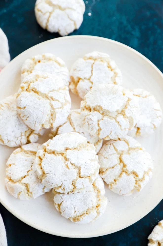 pretty cracked amaretti cookies on plate with linen and green countertop