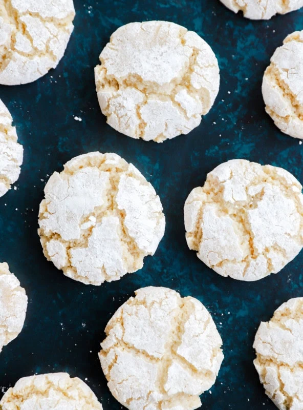 amaretti cookies on green countertop with powdered sugar