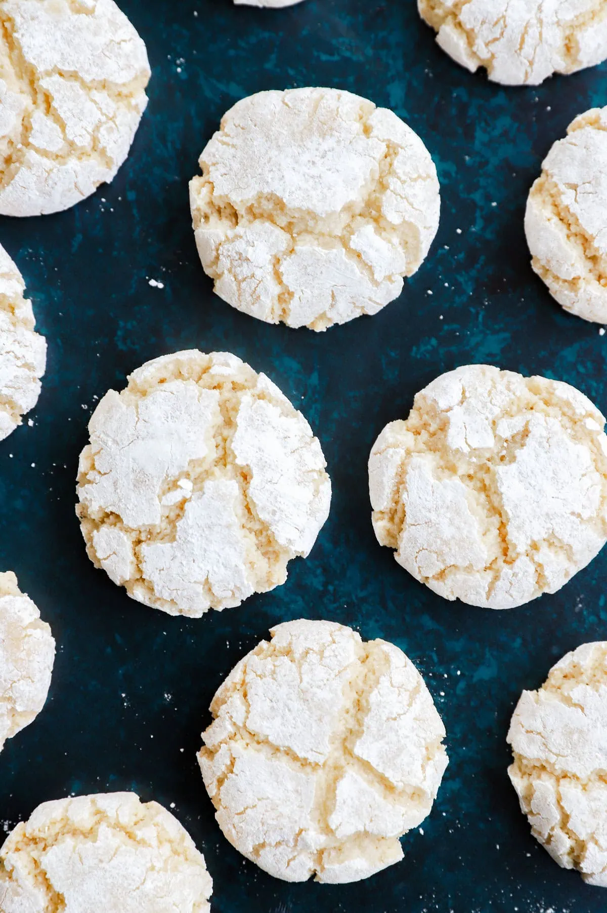 amaretti cookies on green countertop with powdered sugar