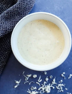 homemade caesar salad dressing in a bowl with cheese on the side