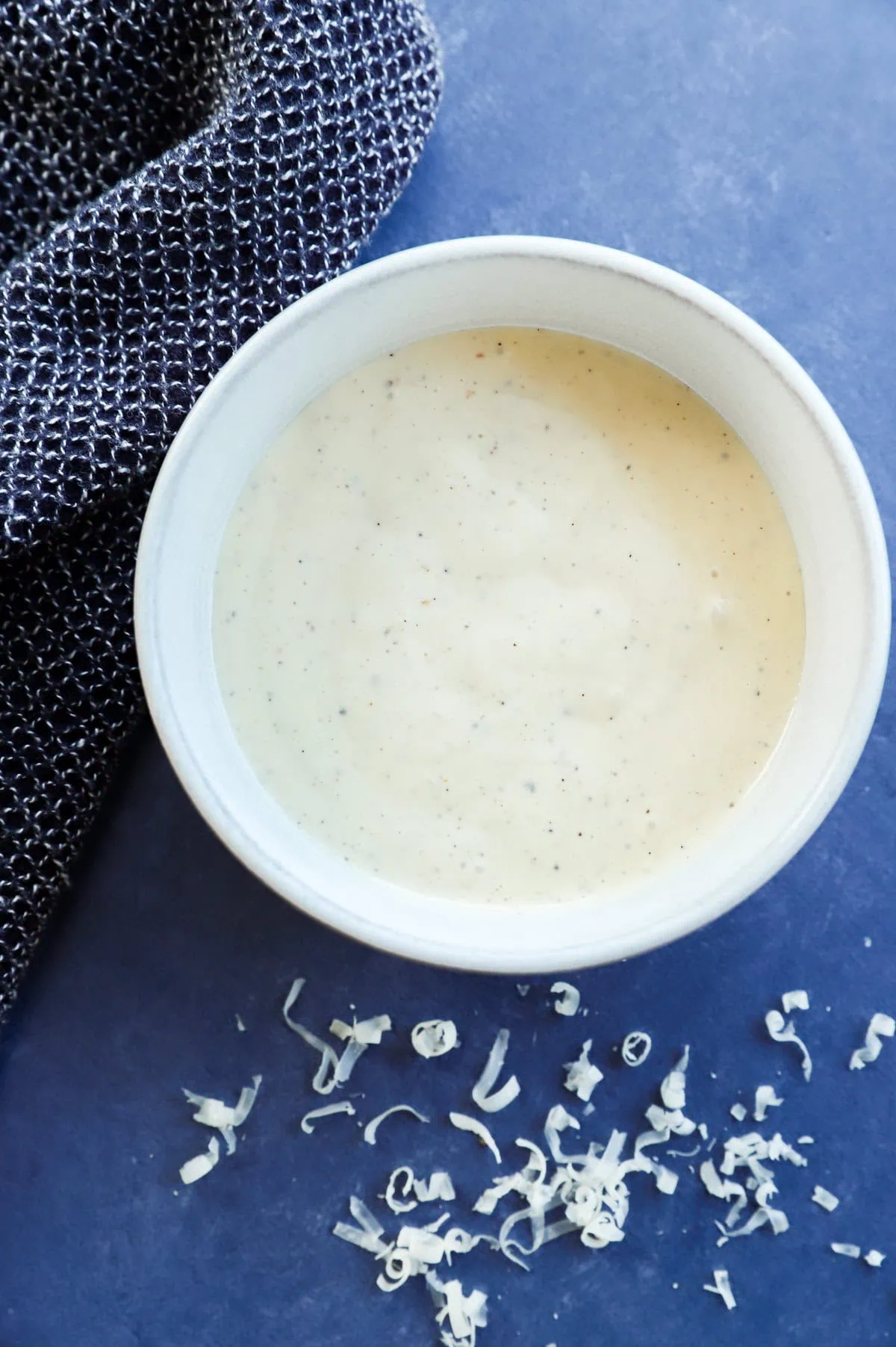 homemade caesar salad dressing in a bowl with cheese on the side