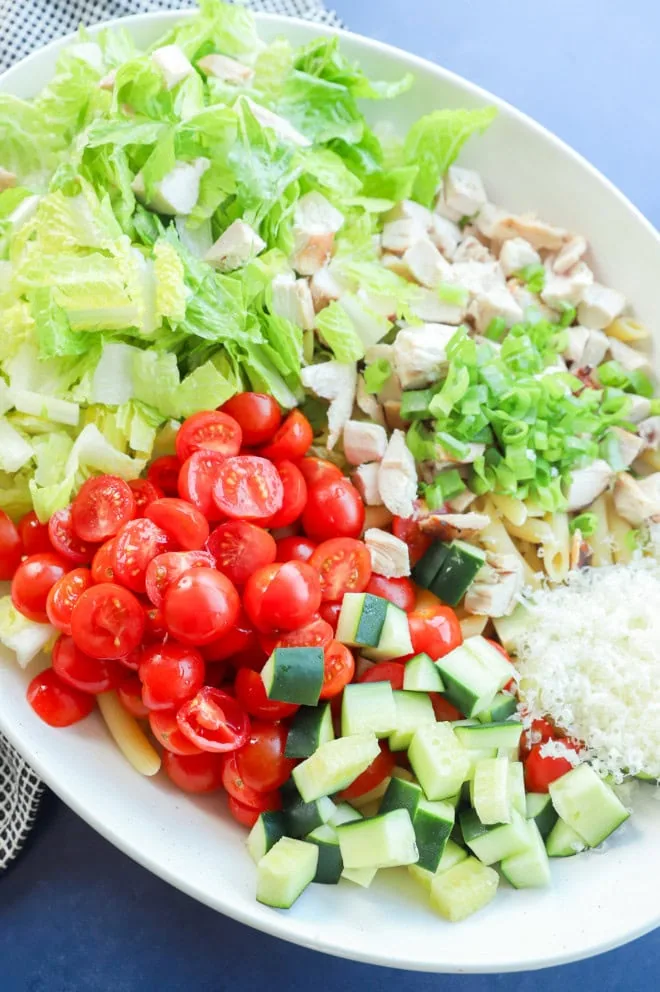 chicken caesar pasta salad ingredients in a bowl before adding dressing