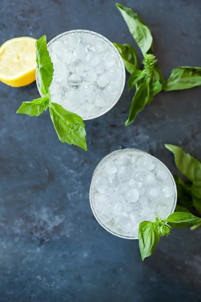 fresh gin basil smash cocktails in glasses with fresh basil and lemon half