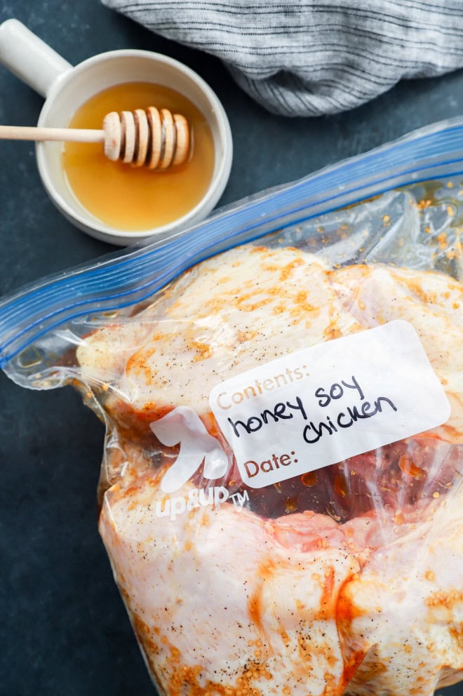 bowl of honey with honey stick and chicken in a bag marinating