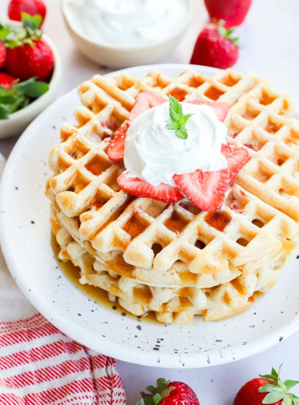 Stack of strawberry waffles with syrup on top