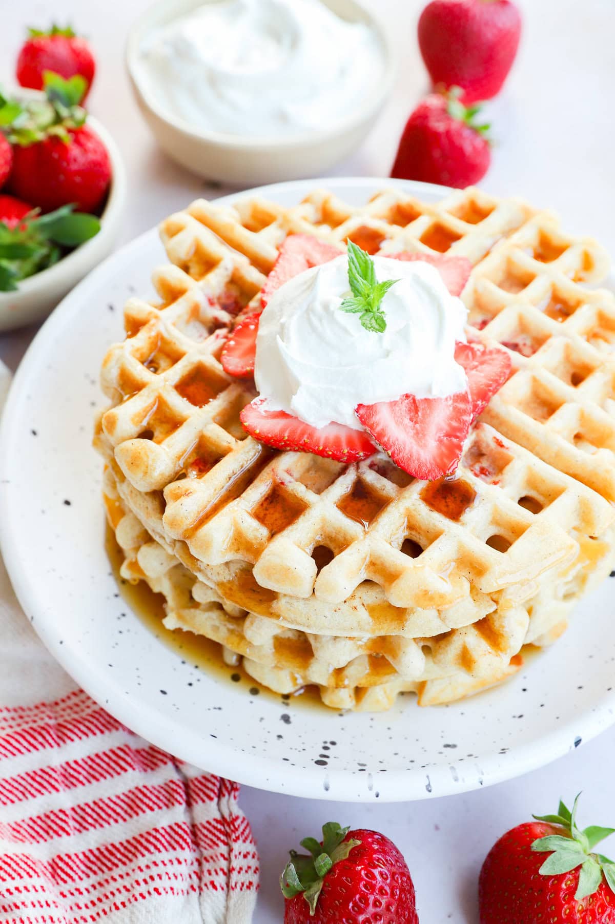 Stack of strawberry waffles with syrup on top