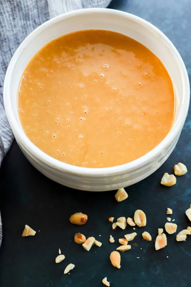 bowl of asian-inspired sauce in a bowl with nuts around