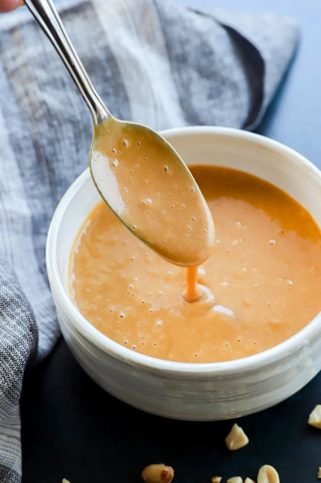 spooning thai peanut dressing into a bowl