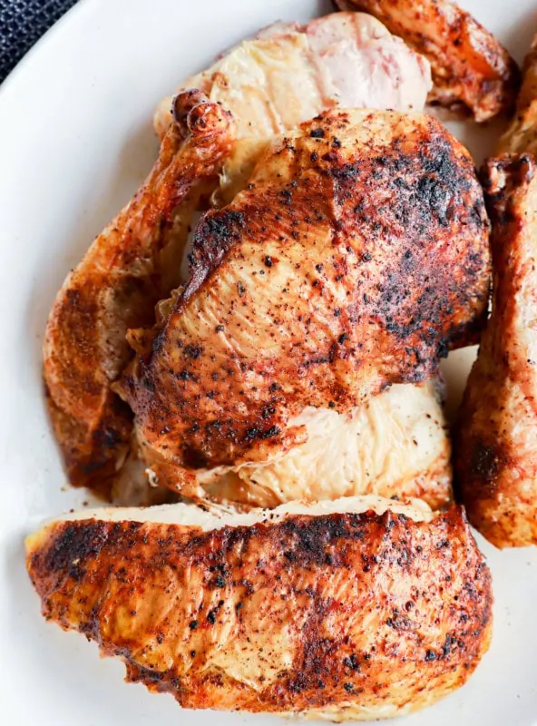 grilled full chicken on platter in pieces with utensils