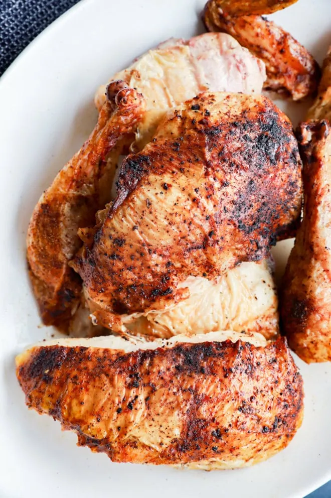 grilled full chicken on platter in pieces with utensils