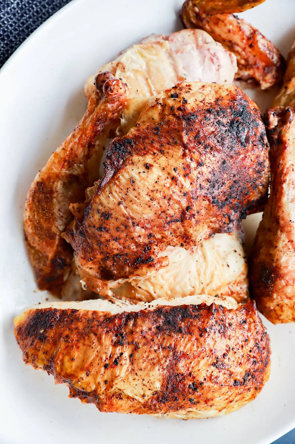 grilled full chicken on platter in pieces with utensils