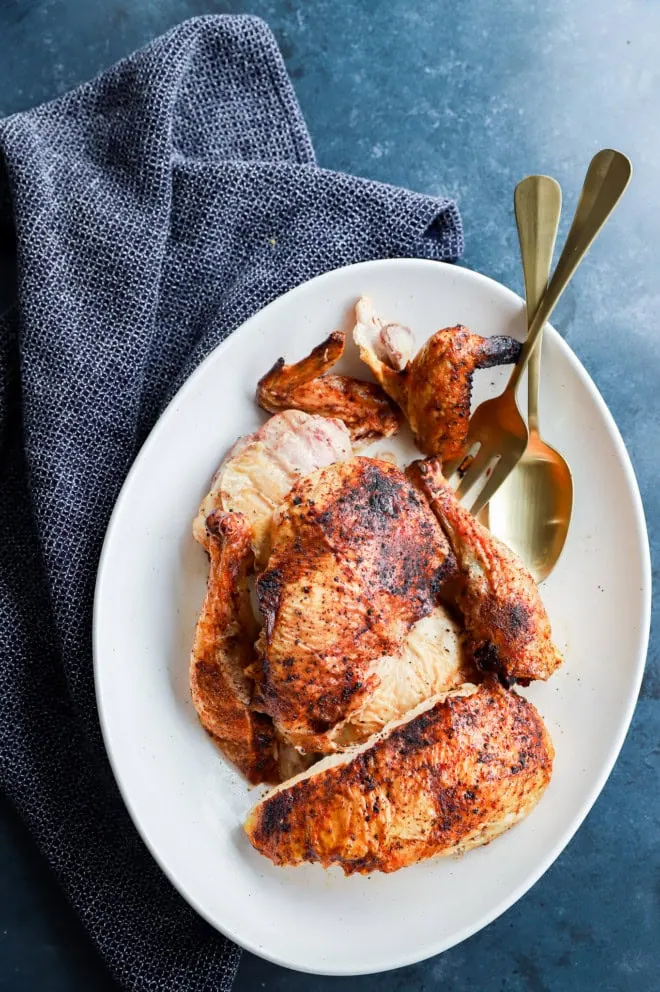 pieces of poultry on serving platter with linen and serving utensils