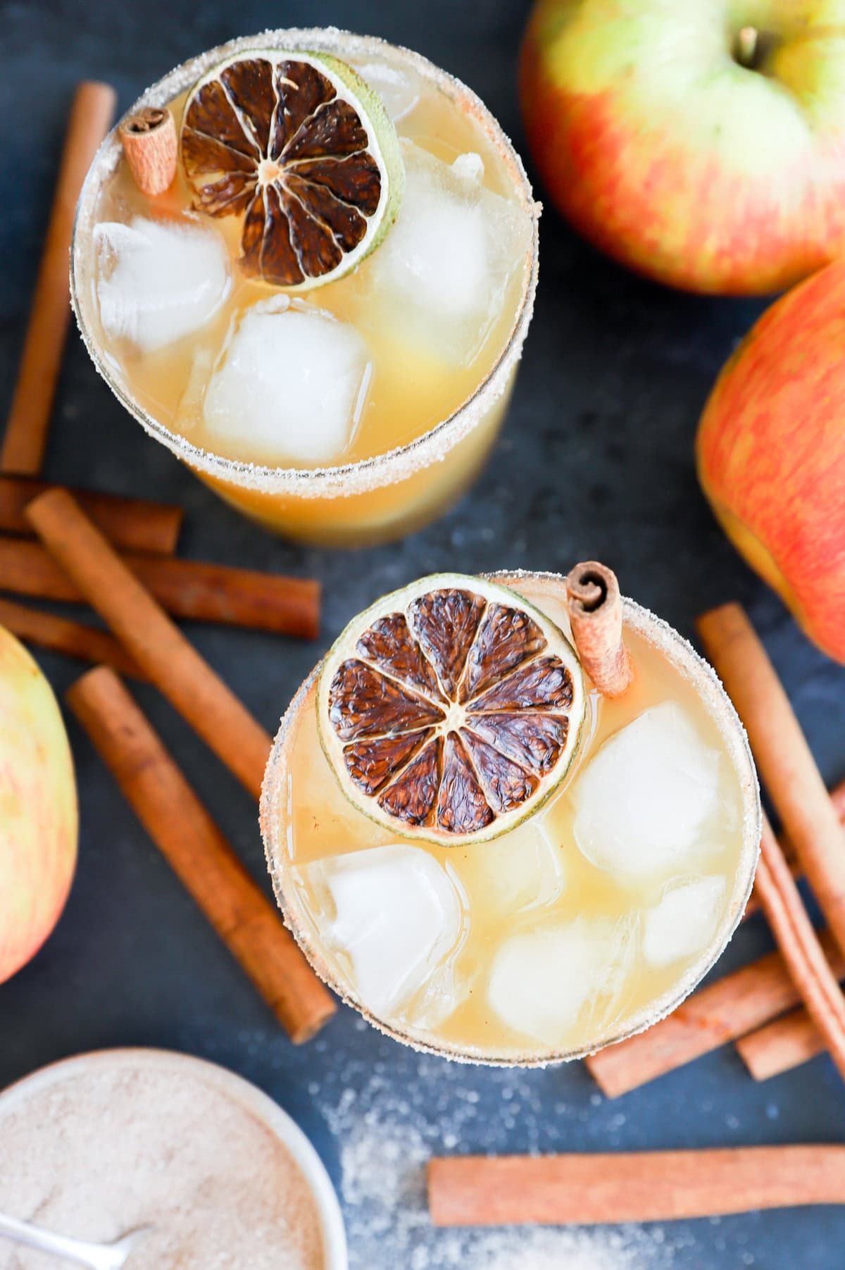 tequila apple cocktail in glasses with cinnamon sticks and fresh apples