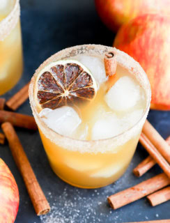 glass of apple fall drink in glass full of ice with cinnamon stick garnish