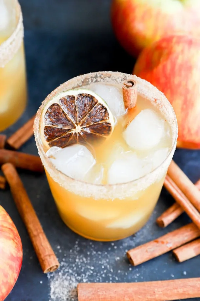 glass of apple fall drink in glass full of ice with cinnamon stick garnish