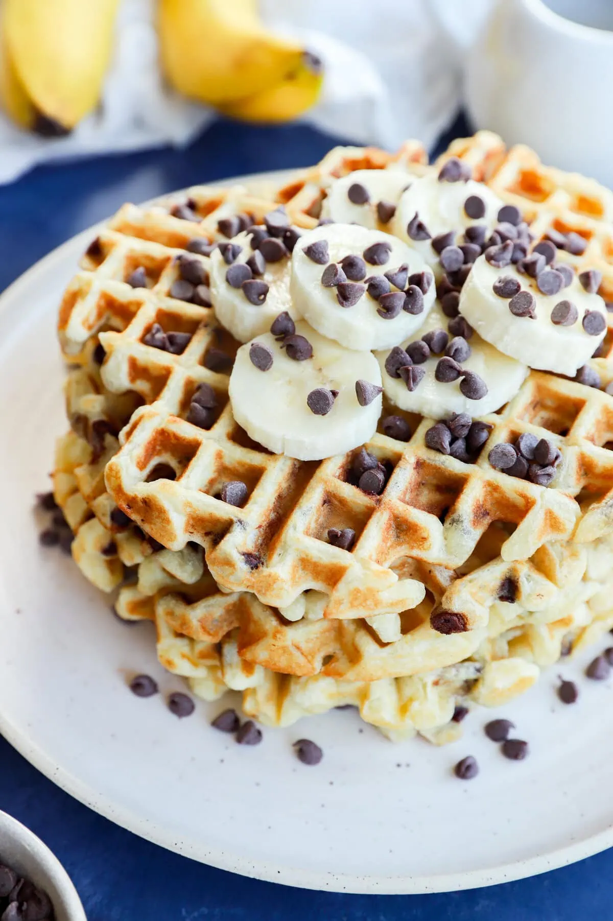 stack of banana chocolate chip waffles with fresh banana slices and chocolate chips